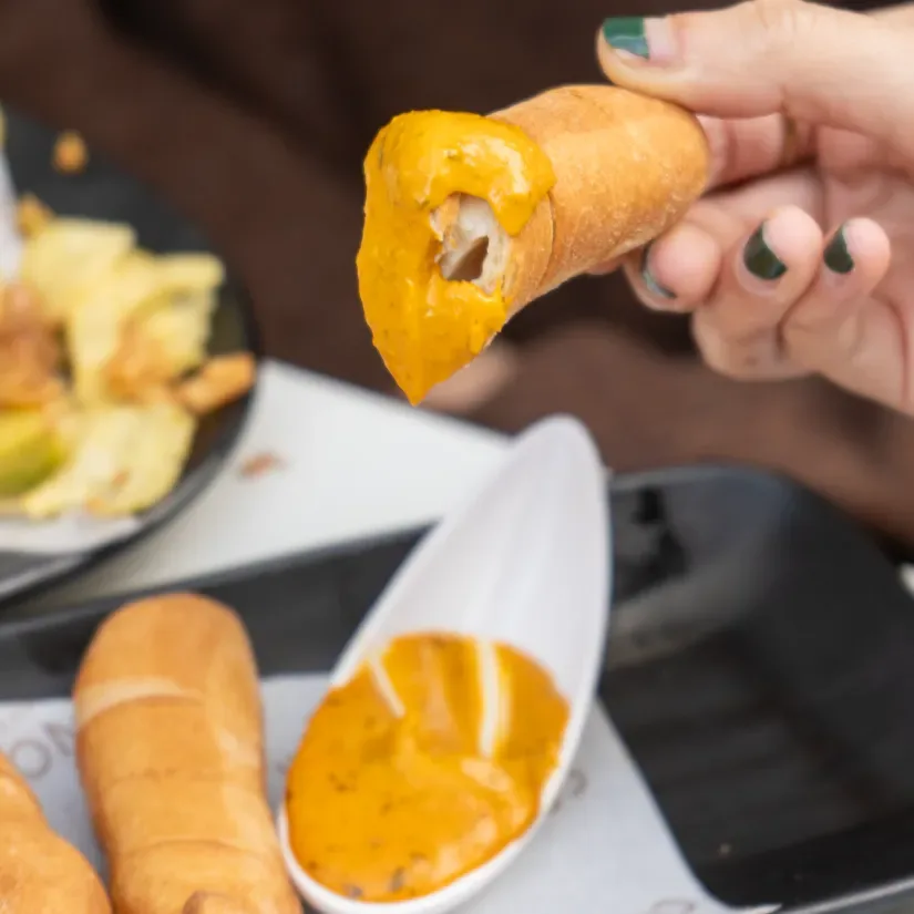 Mano mojando un frito en salsa