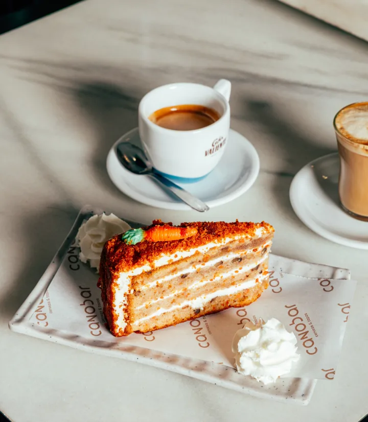 Porción de tarta con nata junto a un café