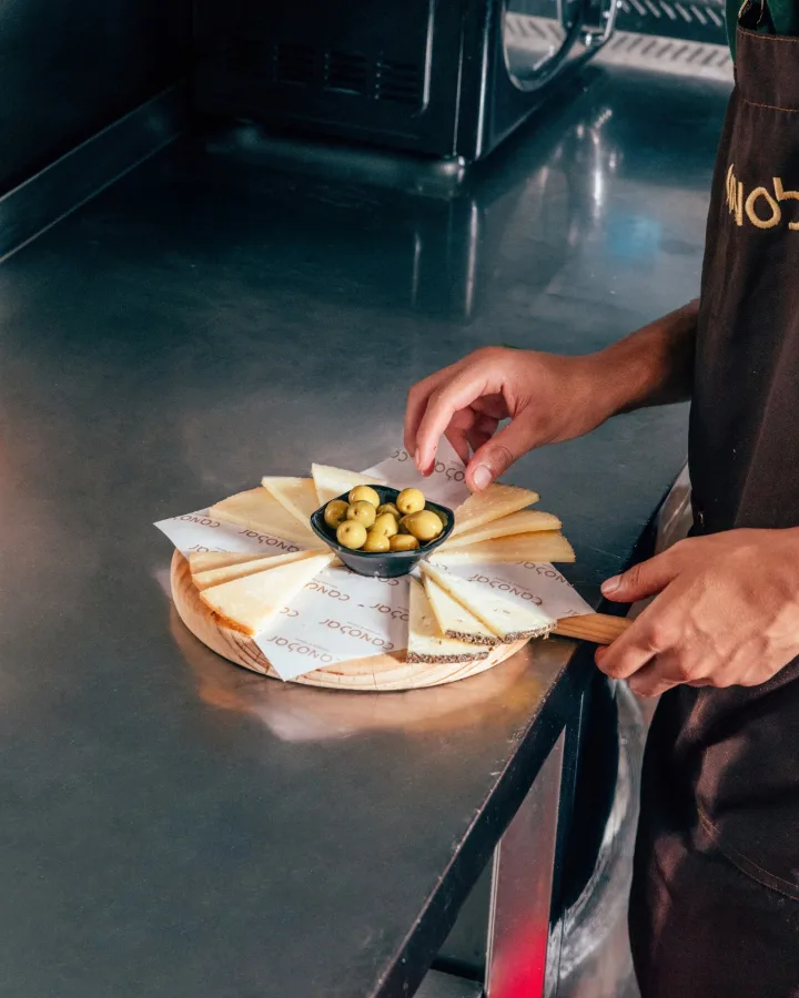En cocina, preparando una tabla de quesos con aceitunas